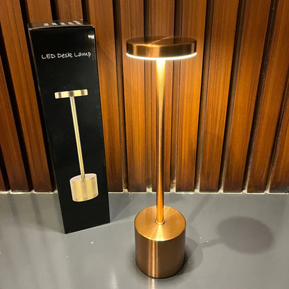 Gold LED desk lamp next to its packaging on a wooden surface