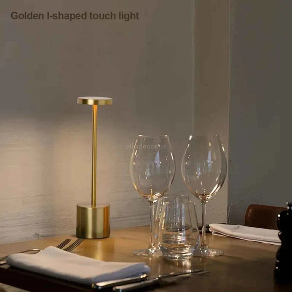 Gold I-shaped touch light on a table with wine glasses and cutlery